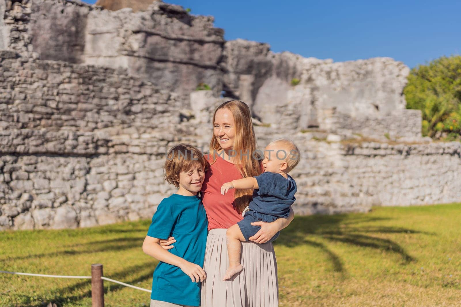 Mother and two sons tourists enjoying the view Pre-Columbian Mayan walled city of Tulum, Quintana Roo, Mexico, North America, Tulum, Mexico. El Castillo - castle the Mayan city of Tulum main temple by galitskaya