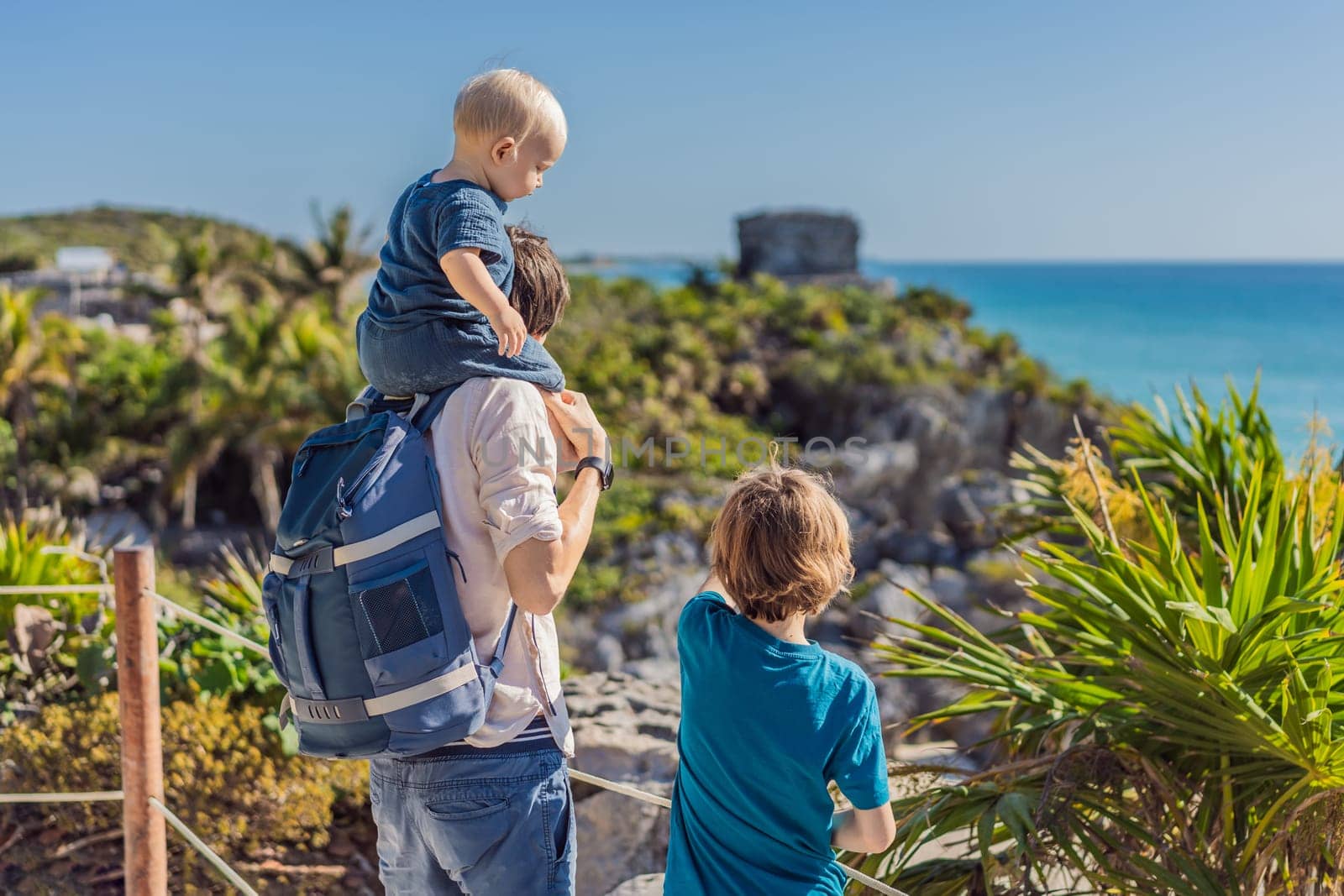 Father and two sons tourists enjoying the view Pre-Columbian Mayan walled city of Tulum, Quintana Roo, Mexico, North America, Tulum, Mexico. El Castillo - castle the Mayan city of Tulum main temple.