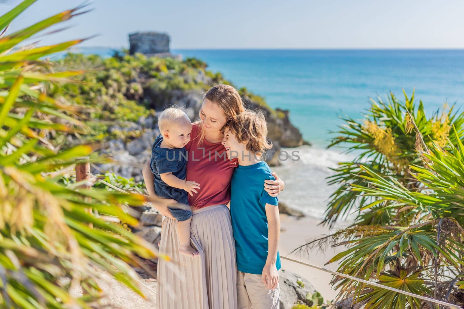 Mother and two sons tourists enjoying the view Pre-Columbian Mayan walled city of Tulum, Quintana Roo, Mexico, North America, Tulum, Mexico. El Castillo - castle the Mayan city of Tulum main temple by galitskaya