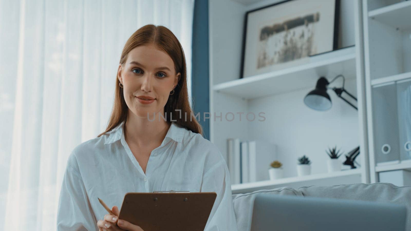Friendly psychologist woman in clinic office professional portrait with smile and holding clipboard for patient to visit psychologist. The experienced and prim confident psychologist