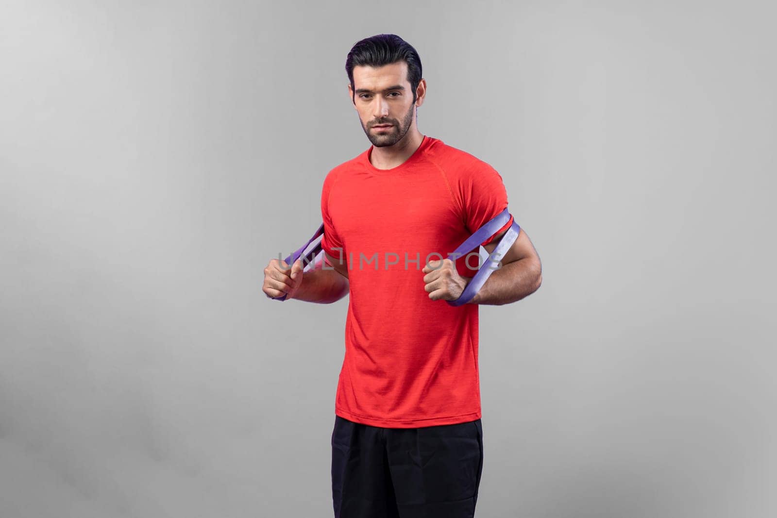 Full body length gaiety shot athletic and sporty young man with fitness elastic resistance band in standing posture on isolated background. Healthy active and body care lifestyle.