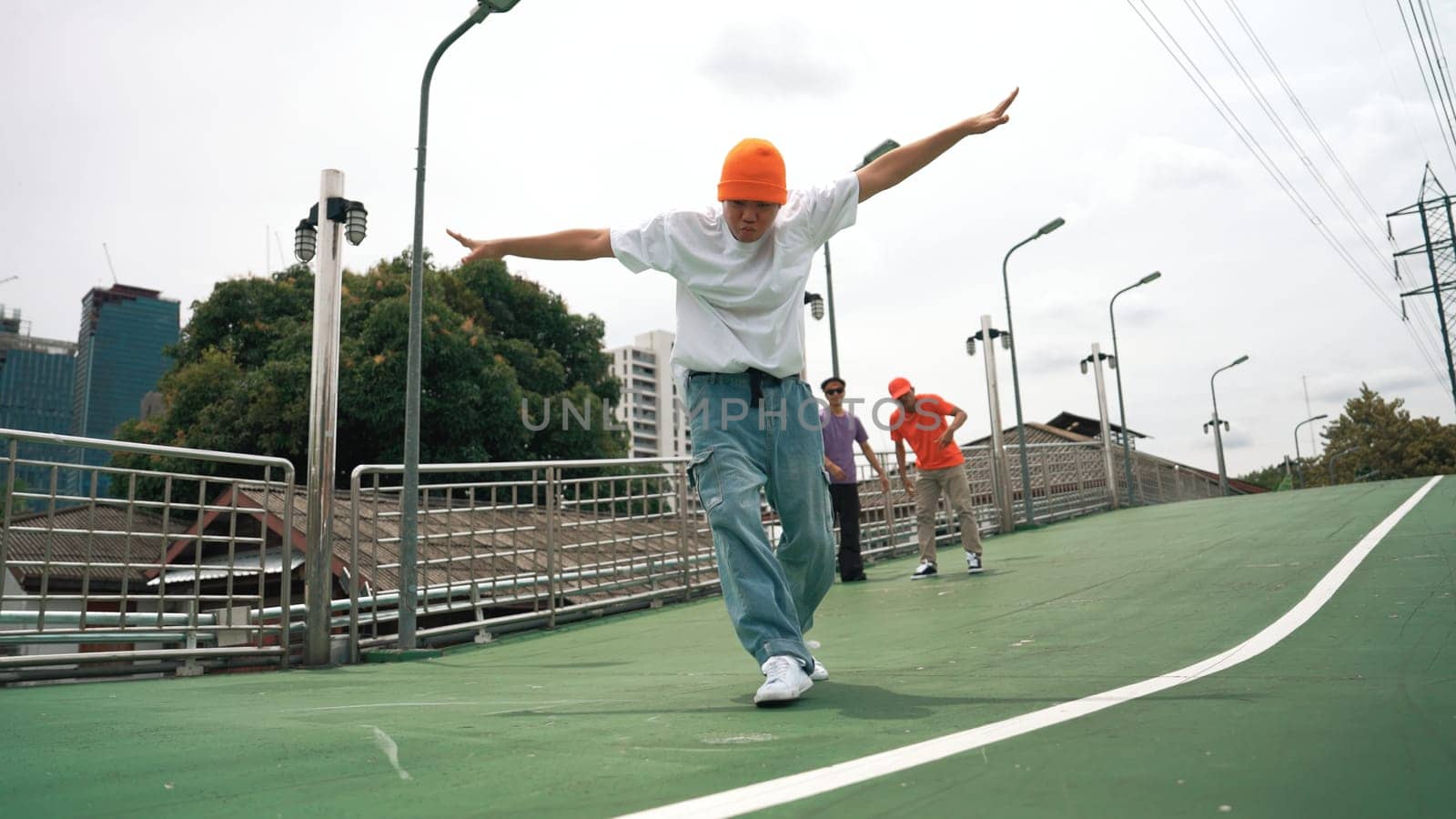 Professional hipster walking while doing freeze pose at bridge. Break dancer perform hip hop footstep surrounded by group of hipster cheering or encouraging friend. Outdoor sport 2024. Sprightly.
