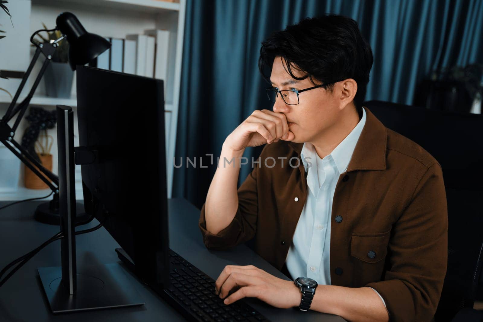 Smart businessman in casual day focusing computer to create business plan report over late night time at office, working on searching tools market planning with new startup company project. Infobahn.