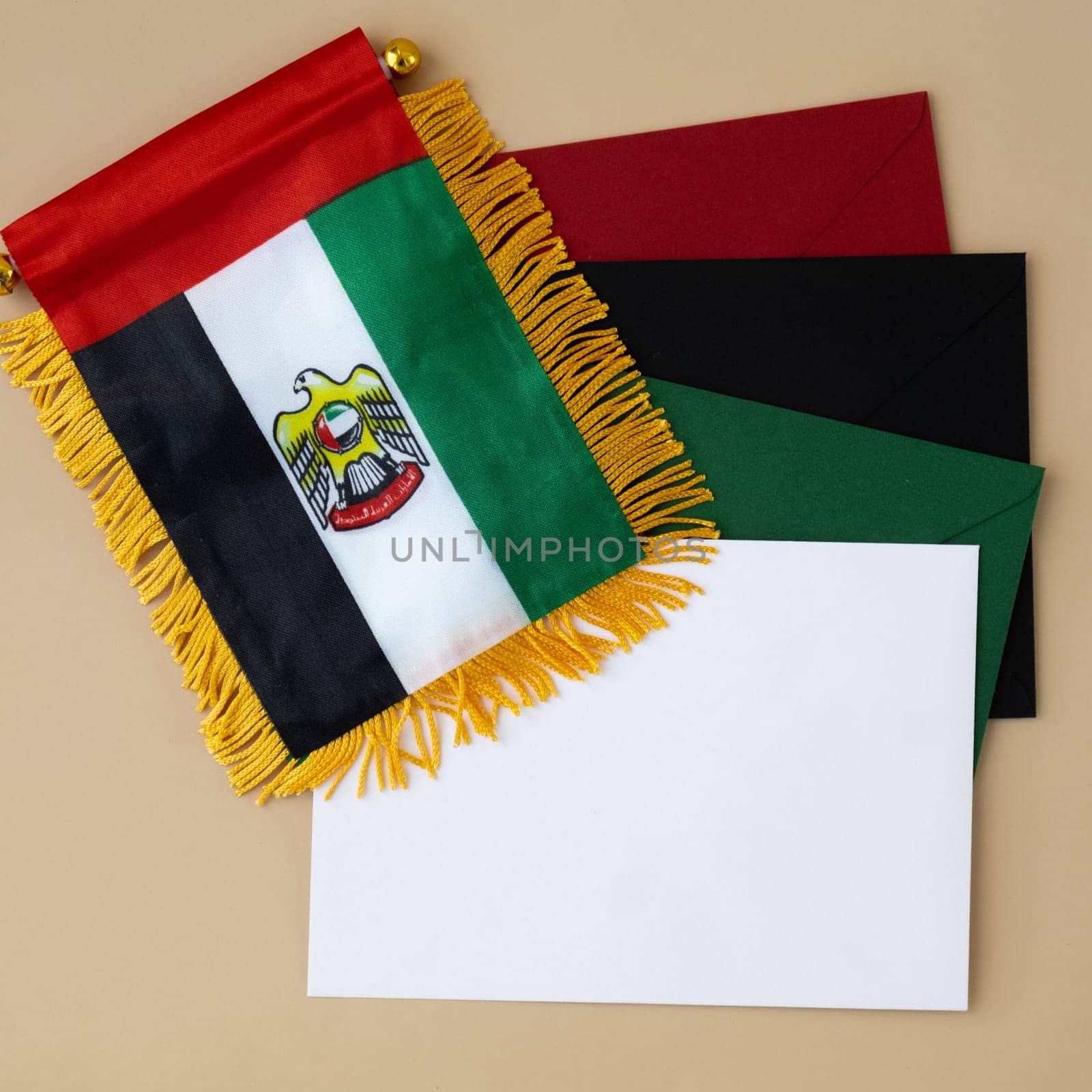 Small flag of UAE on beige background with colorful envelopes. Copy space. Mock up advertisement template. Tourism travel voucher with United Arab Emirates national symbol. Visit Dubai concept