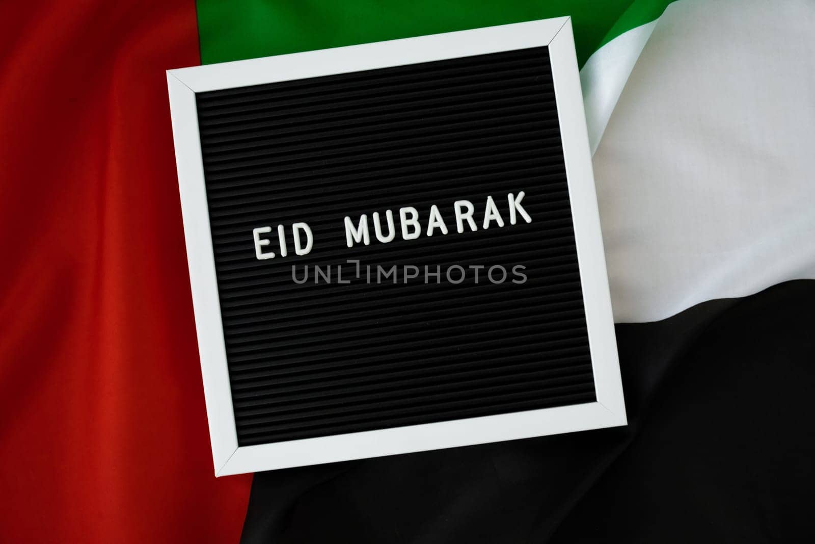 Message text EID MUBARAK - happy holidays waving UAE flag on background concept. Greeting card advertisement. Commemoration Day Muslim Ramadan Blessed holy month public holiday. Patriotism