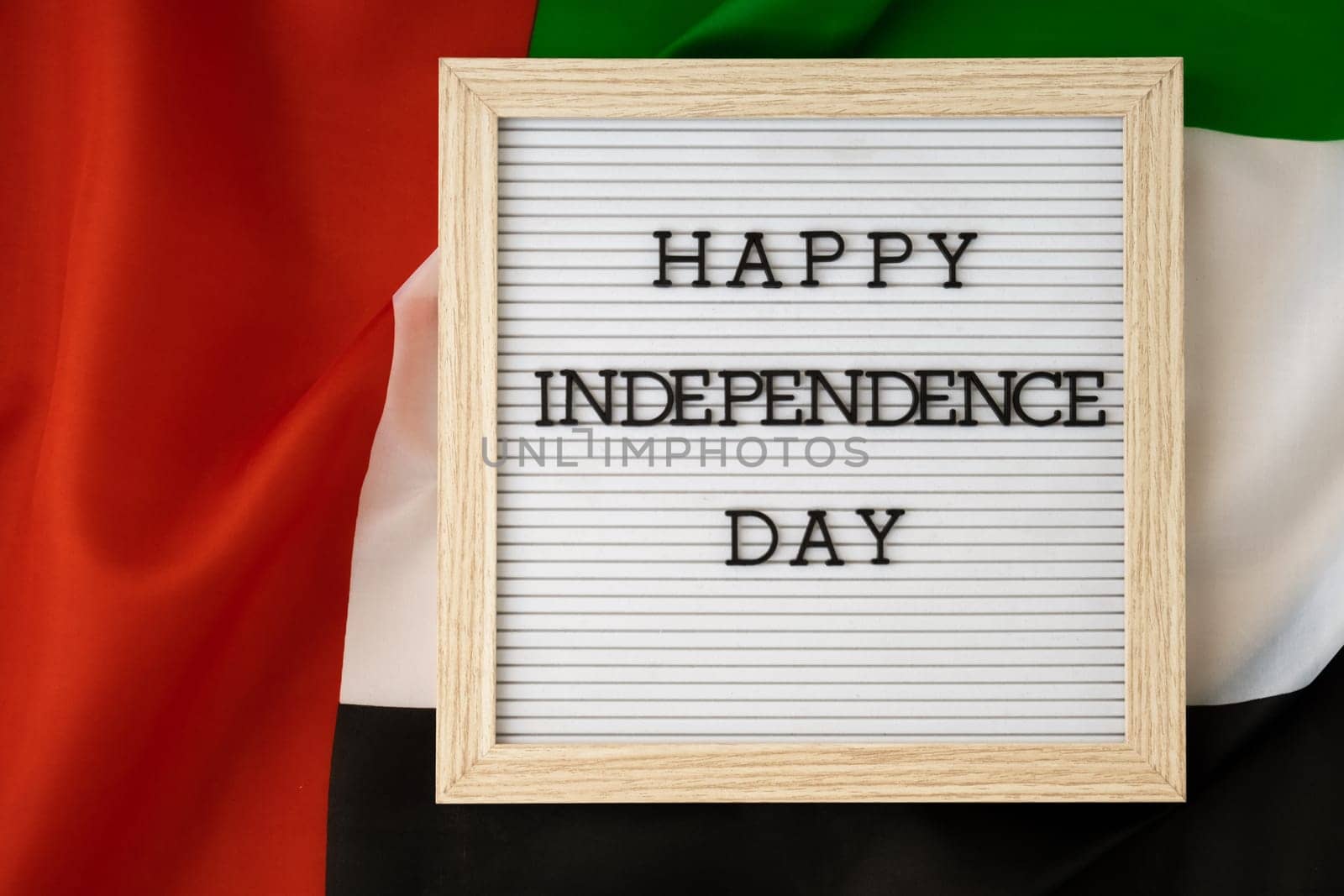 Text HAPPY INDEPENDENCE DAY on background waving flag of UAE. National holiday of United Arab Emirates. Commemoration Day Muslim Arabian holidays. Dubai celebration