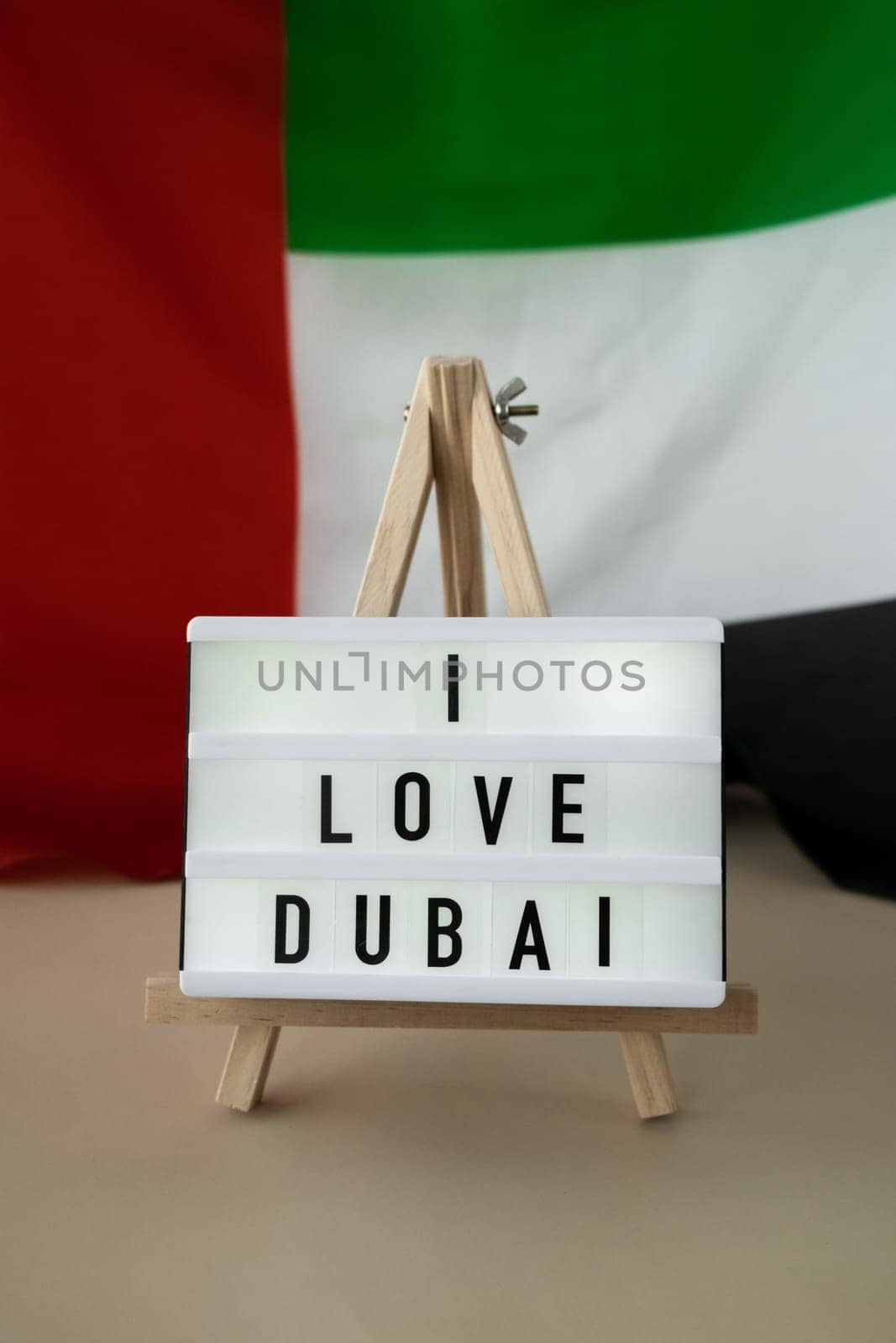Message text I LOVE DUBAI on background of waving UAE flag made from silk. United Arab Emirates flag with concept of tourism and traveling. Inviting greeting card, advertisement. Dubai welcoming card