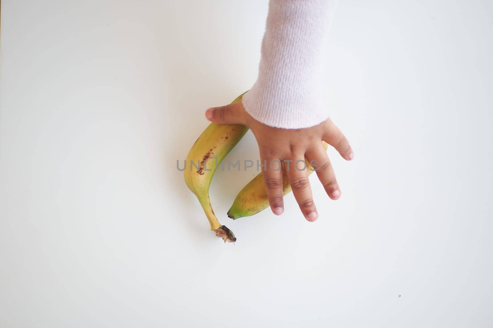 top view of child hand reaching for a banana ,