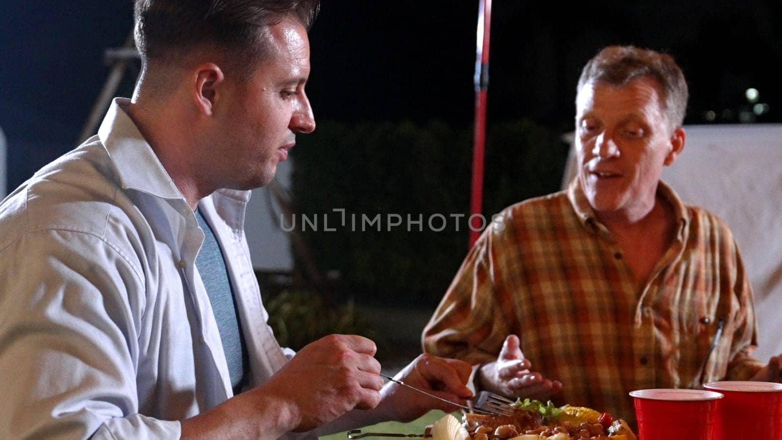 Family gather celebrate holiday. Focus father and grandfather talk about good news and have dinner party food. Outdoor activity for spending time with multigeneration cross generation gap. Divergence.