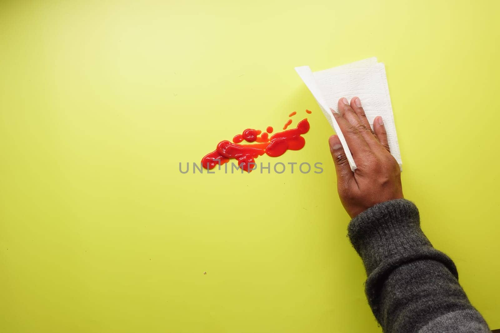 hand in blue rubber gloves cleaning tomato spill with a tissue ,