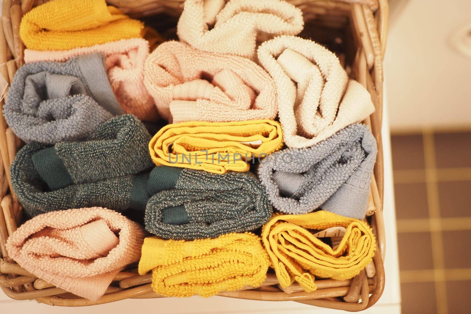 A storage basket made of wood filled with an assortment of towels.