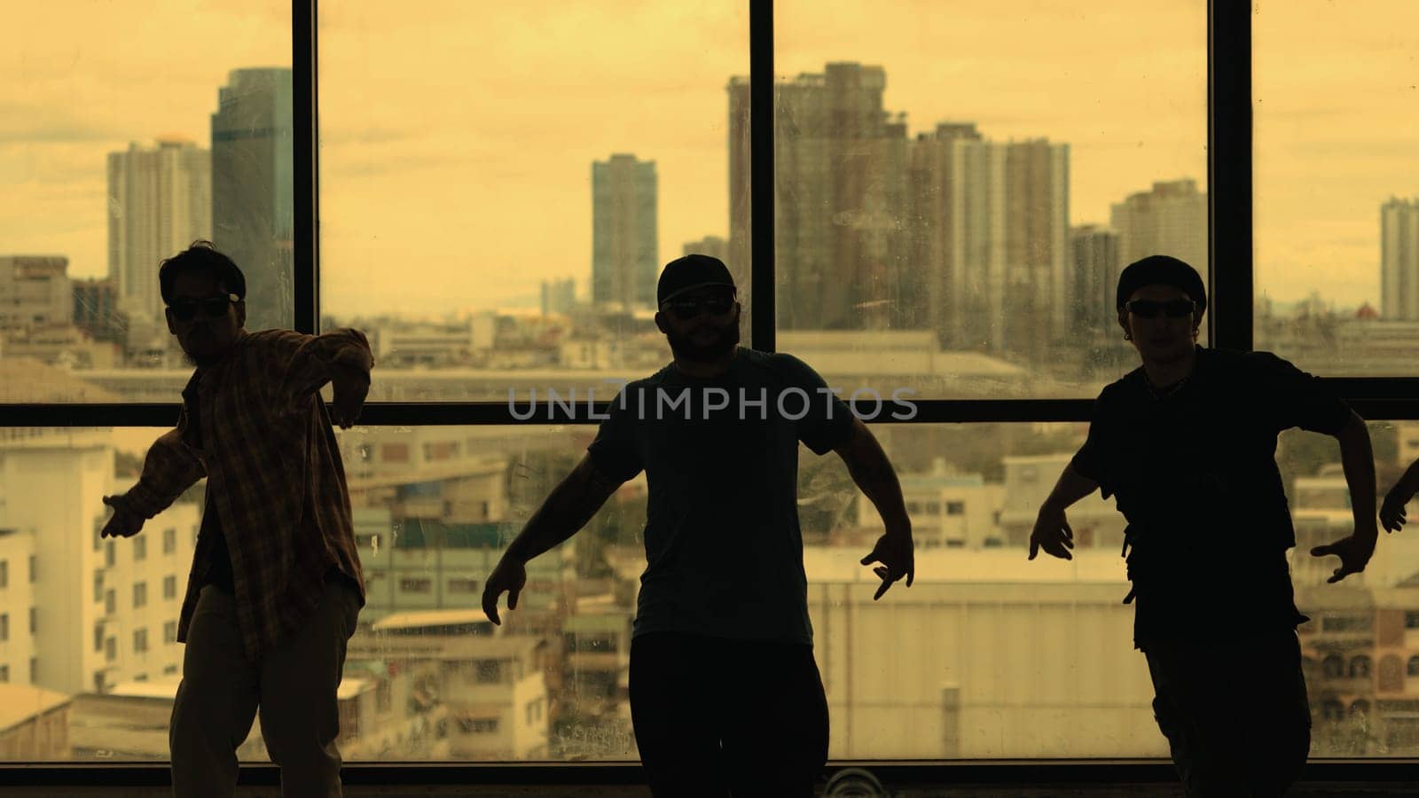 Silhouette shot of skilled choreographer group dancing together with sky scrapper, cityscape background. Young hipster team dancing performance. Yellow filter. Shadow. Outdoor sport 2024. Endeavor.