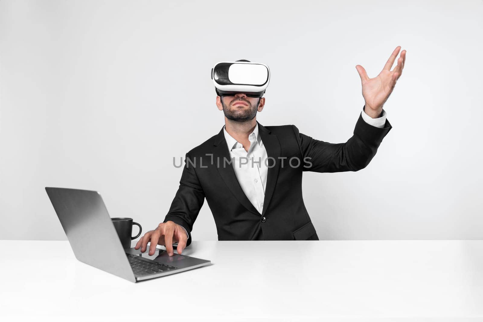 Skilled business man looking at data analysis while sitting at table with laptop and wearing VR glasses. Project manager working by using virtual reality system or connecting at metaverse. Deviation.