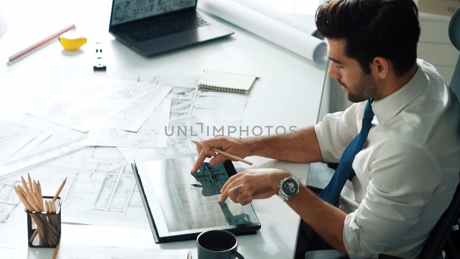 Architect engineer using laptop planning house design at office while sitting at meeting table with blueprint and equipment scatter around.Skilled civil engineer working at blueprint. Alimentation.