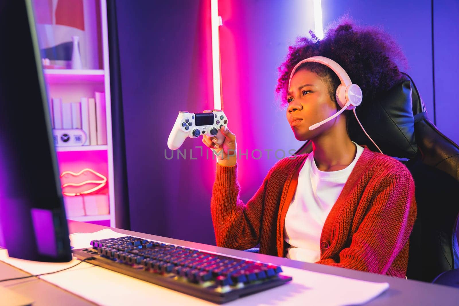 African American girl streamer disappointed playing online fighting with Esport skilled team wearing headphones in neon room. Talking other players planing strategies to win competitors. Tastemaker.
