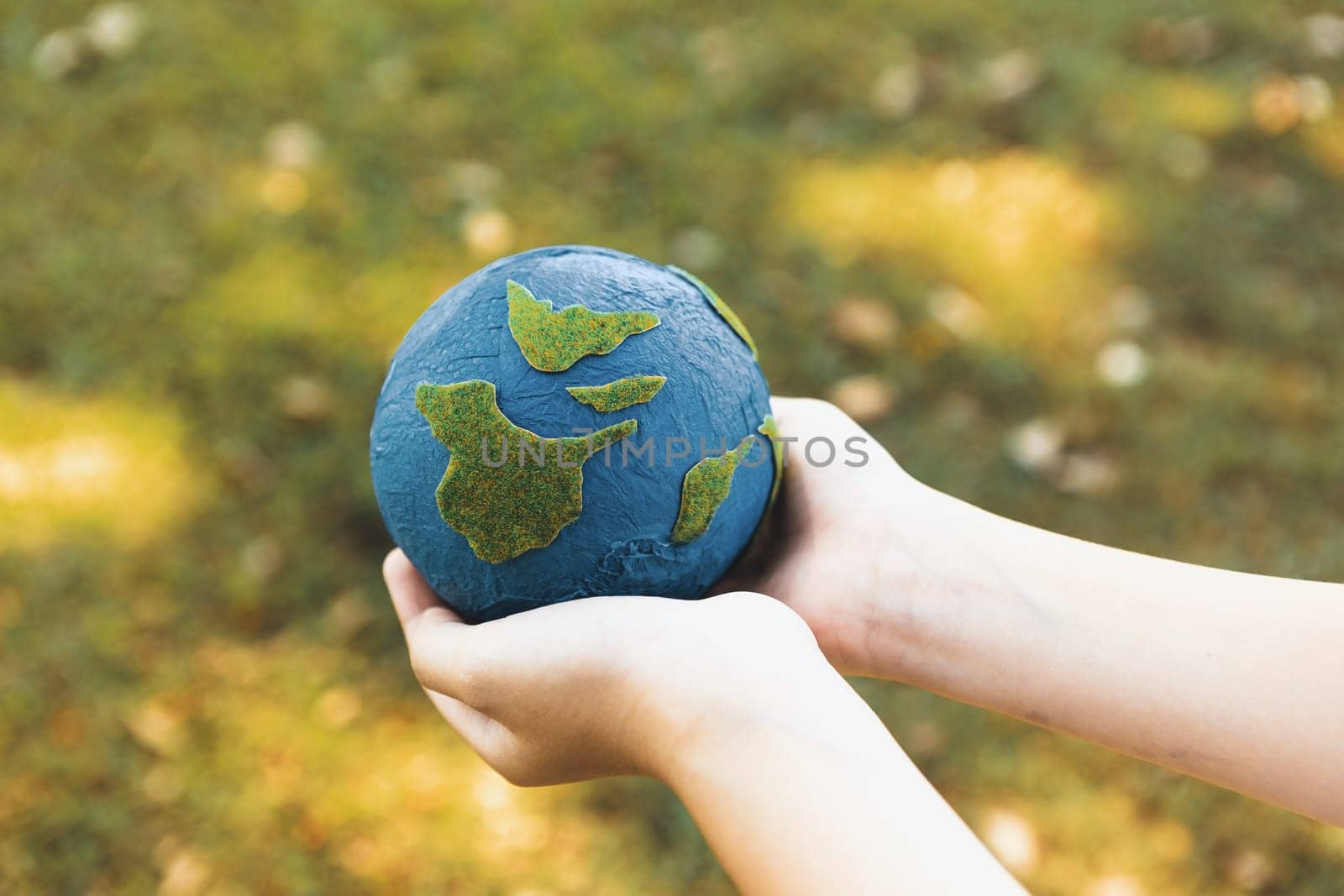 Young boy hand holding planet Earth globe at natural park background. Gyre by biancoblue