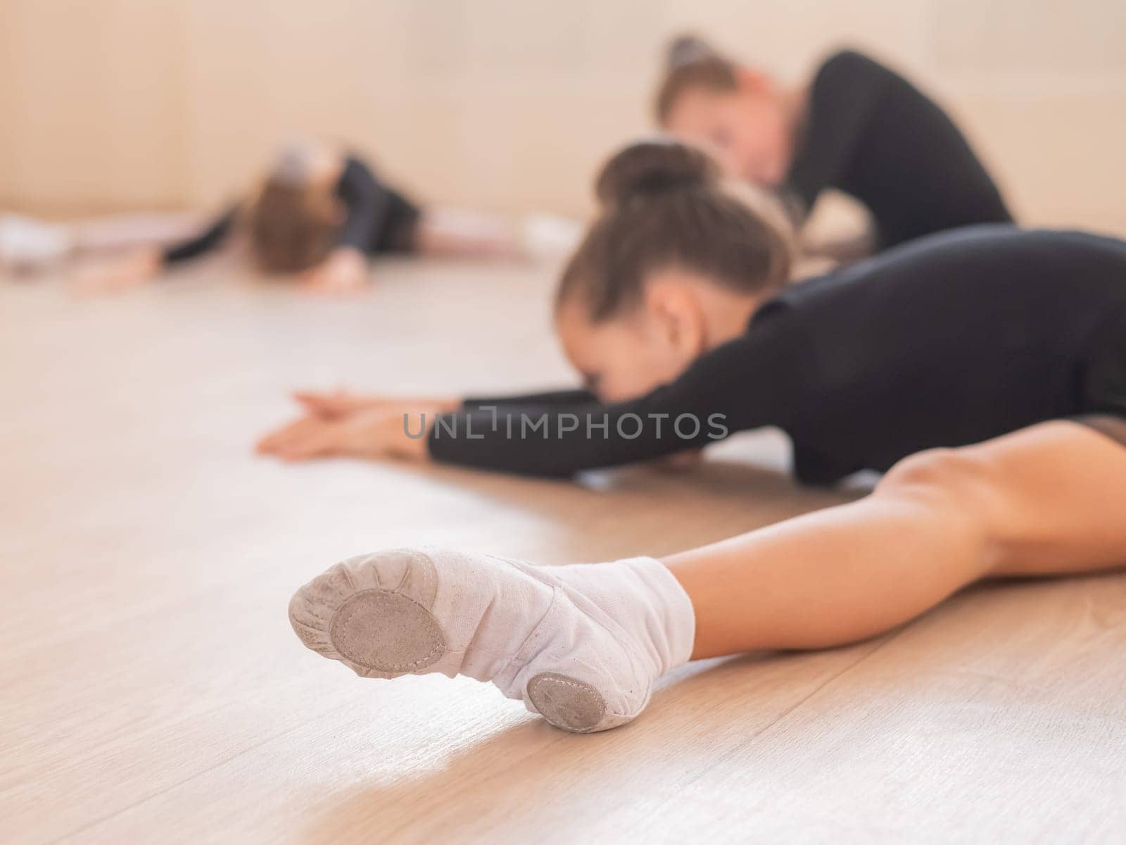 Girls ballerinas stretch while lying in a wide fold