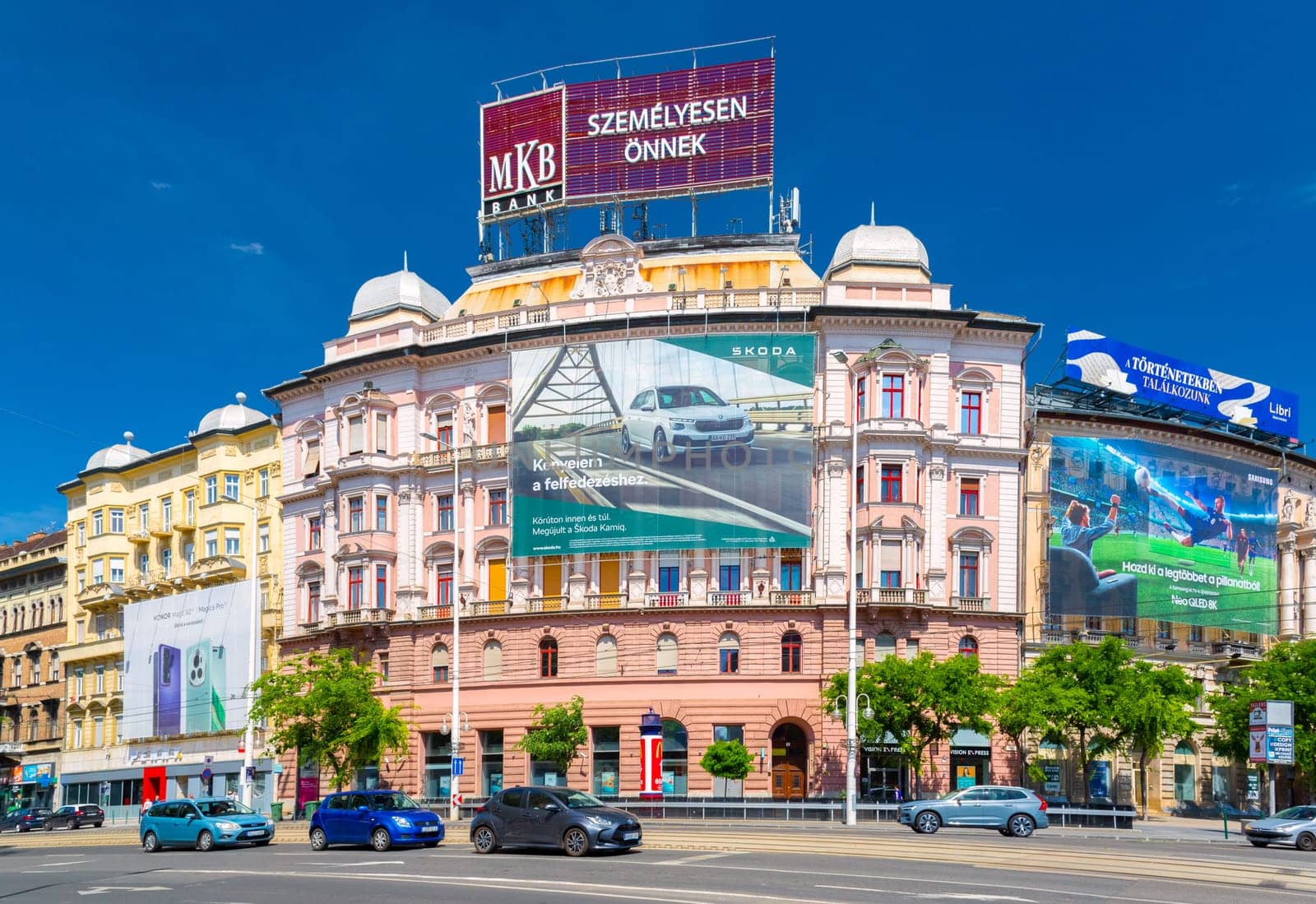 Budapest, Hungary - 1 May 2024: A pink historical building with advertising banners in the intersection of Vaci ut and Terez krt.