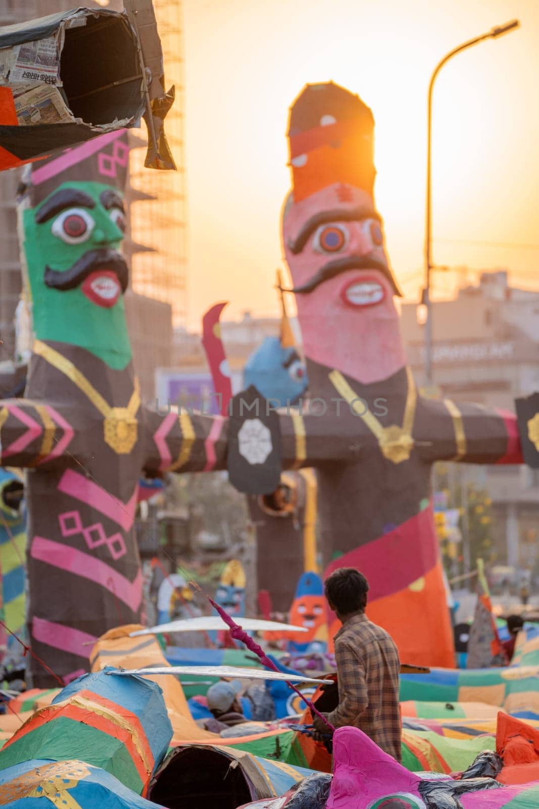 poor labourer looking up at the massive colorful paper effigy of ravan traditionally burnt on the hindu festival of dussehra in India