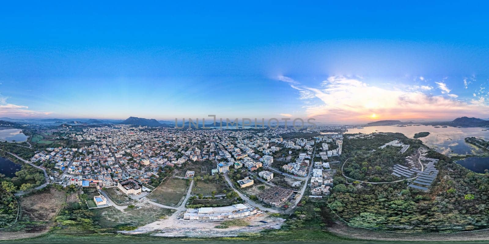 360 spherical image of cityscape of Udaipur city Rajasthan at sunset with houses and trees below and a blue sky of dawn above