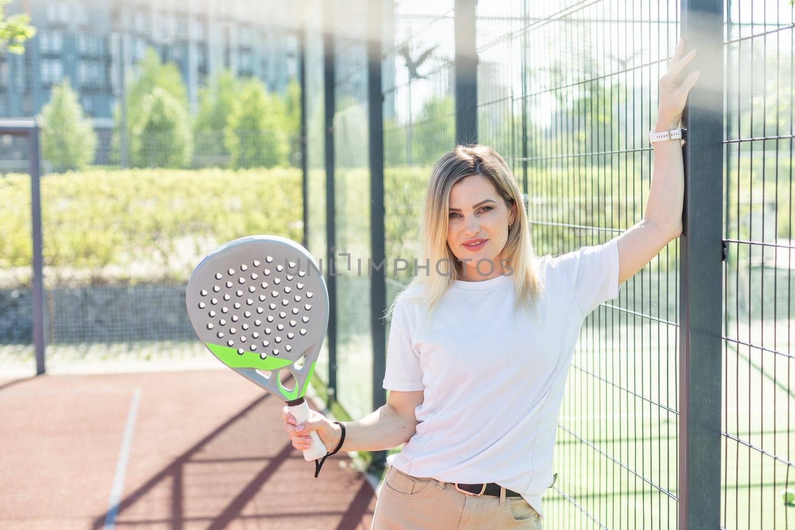 Young sporty woman padel player hitting ball with a racket on a hard court. High quality photo