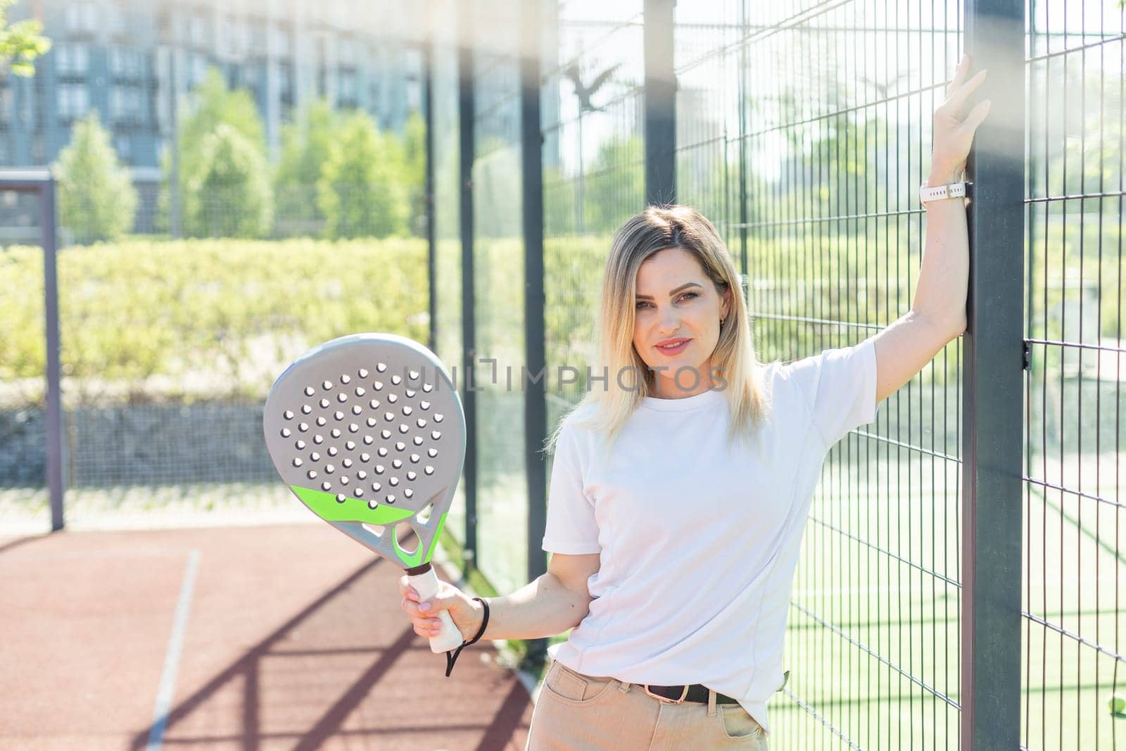 Young sporty woman padel player hitting ball with a racket on a hard court by Andelov13