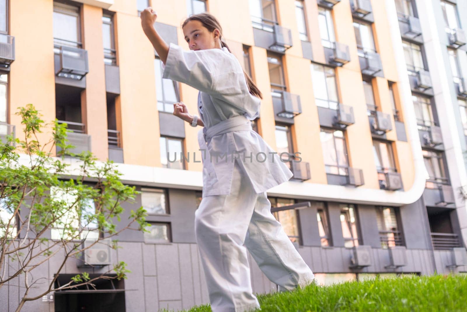 Young active girl wearing in white kimono with white belt performing martial arts kick skills. sporty karate woman improving fight technique on Chinese bridge. concept of sport. by Andelov13