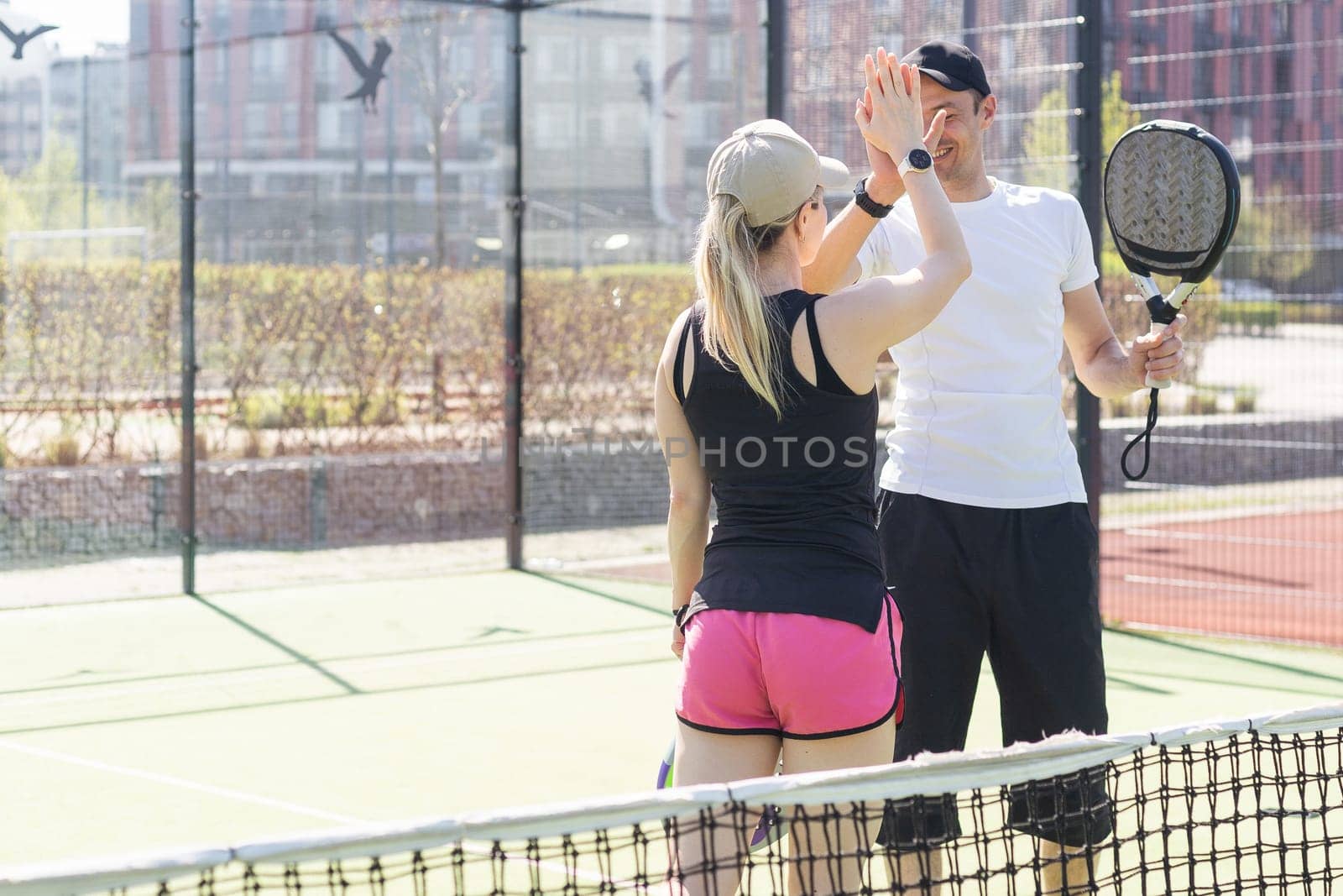 Sports couple with padel rackets posing on tennis court by Andelov13