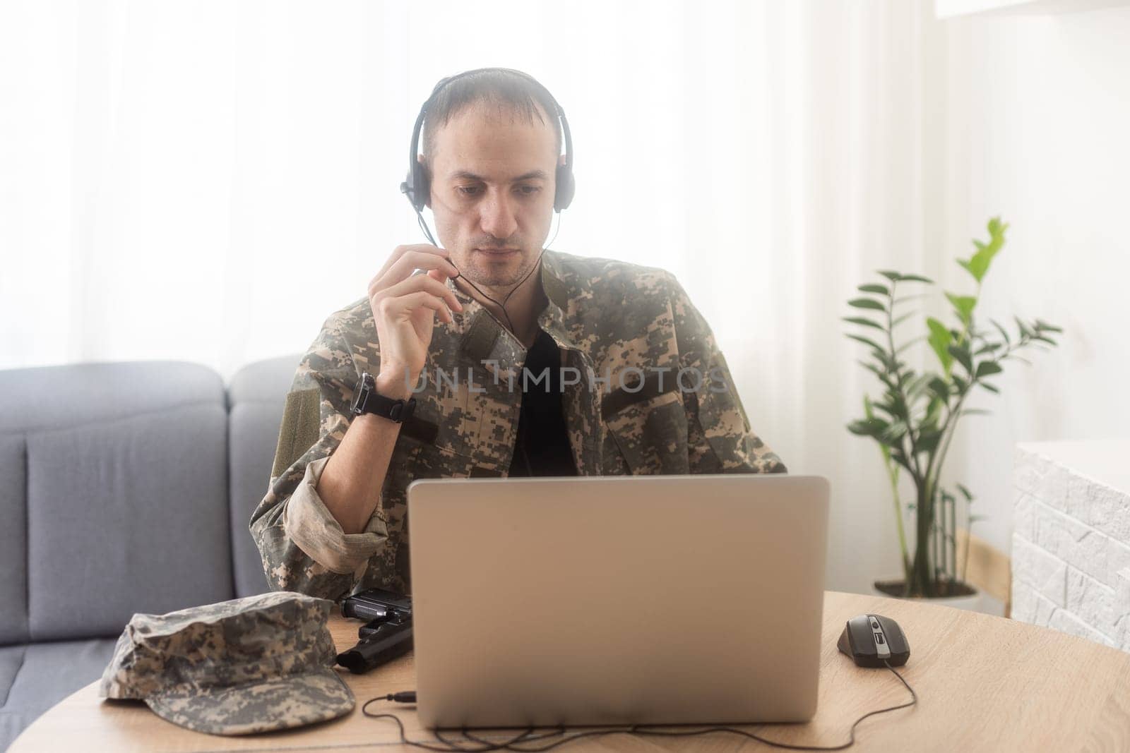Young hispanic man army soldier using laptop sitting on table at home. High quality photo