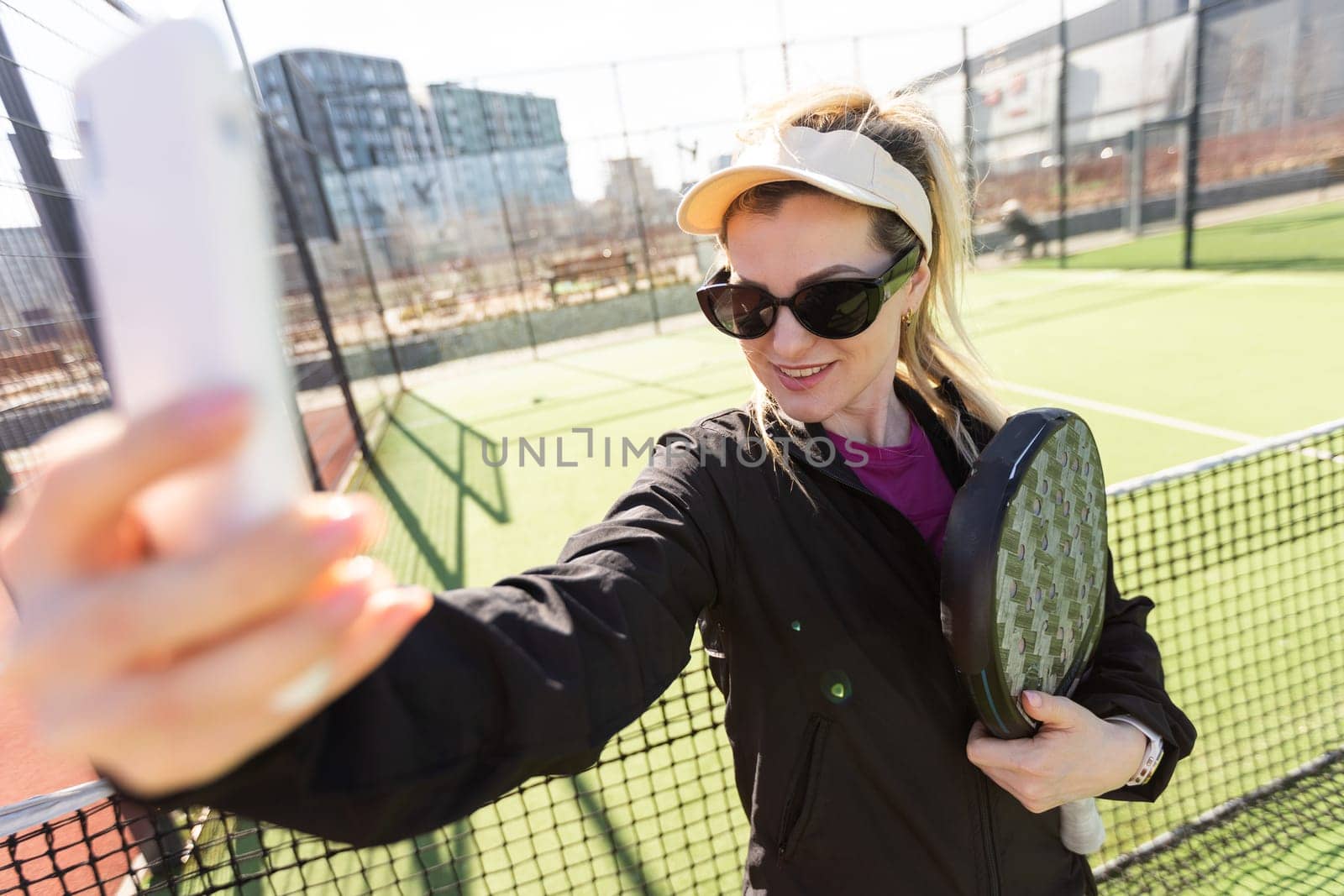 Happy female paddle tennis player during practice on outdoor court looking at camera. Copy space. by Andelov13