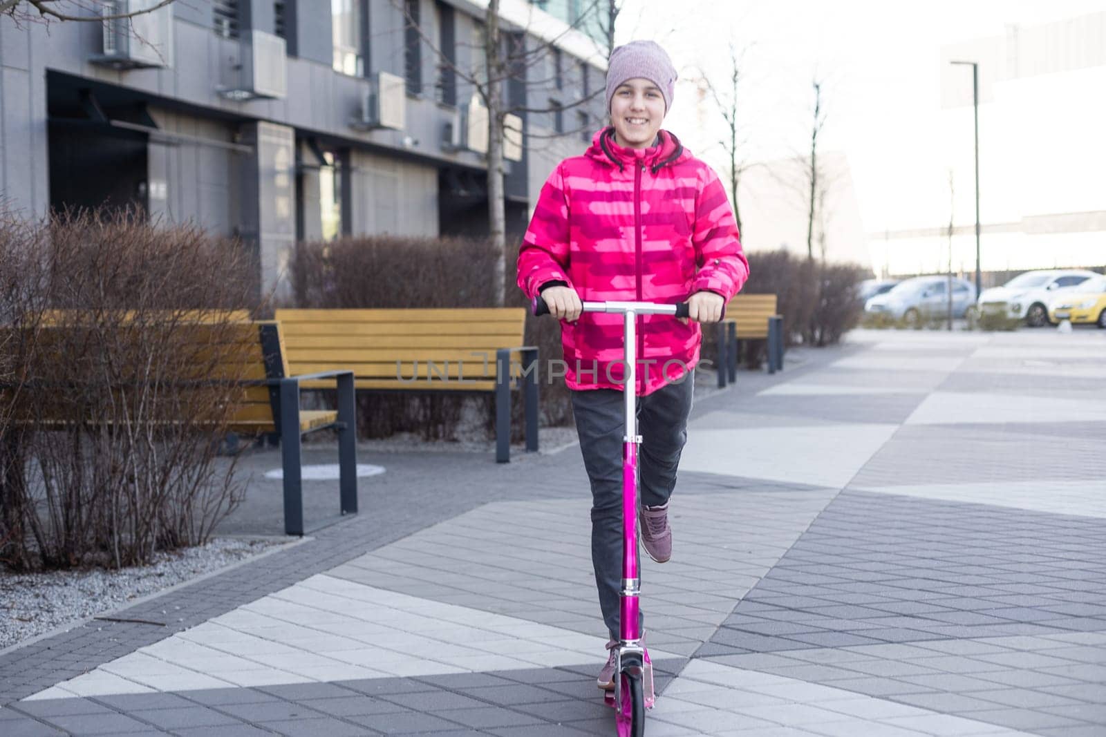 Little cute girl riding a scooter on a path in the park. High quality photo