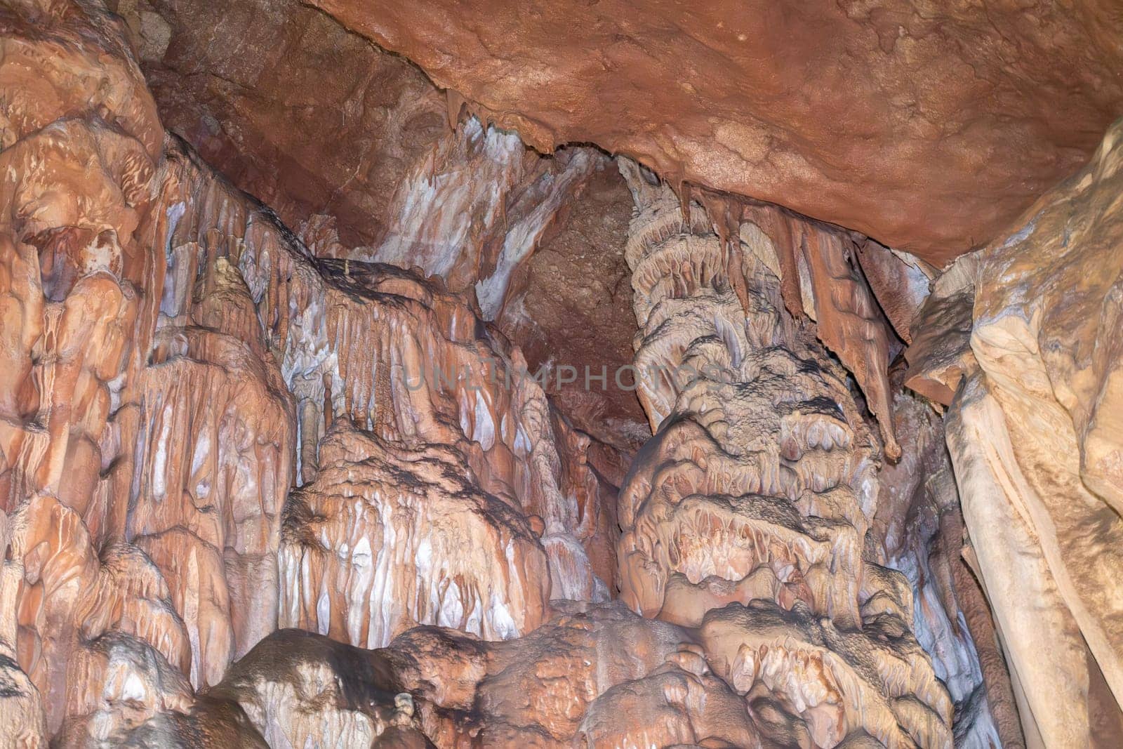 A cave with a lot of rock formations and stalactites hanging from the ceiling. Scene is mysterious and awe inspiring