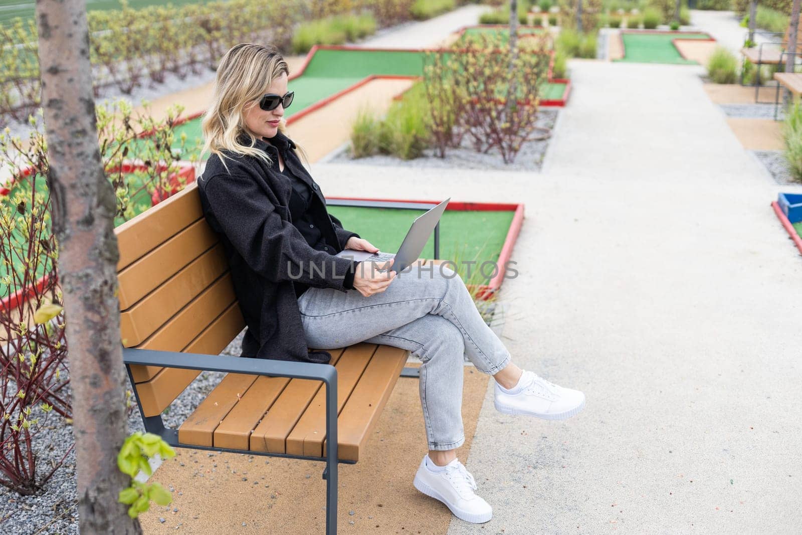 A businesswoman using a laptop on a golf course. High quality photo