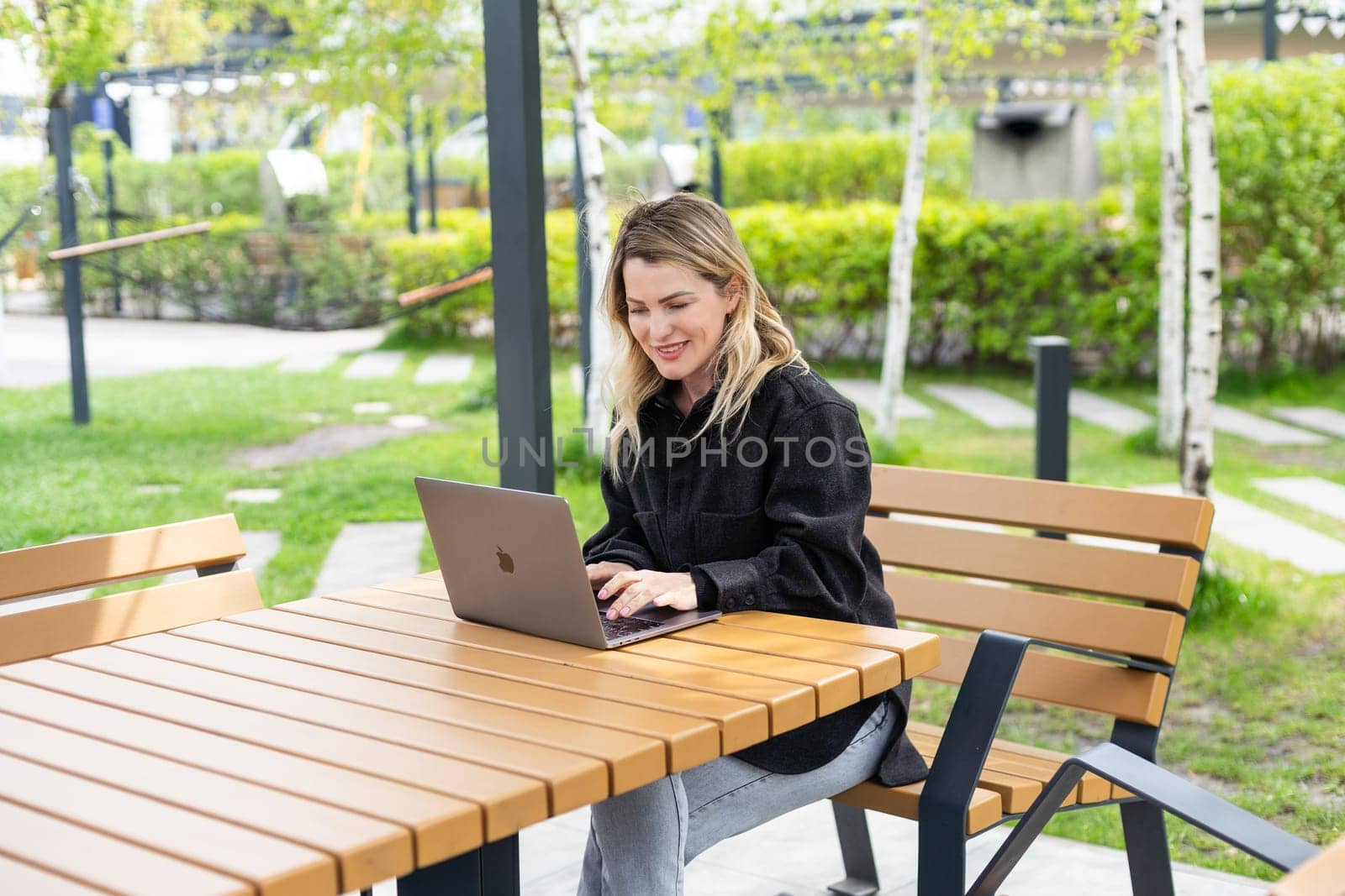 girl with a laptop on a bench in the park on a background of greenery. High quality photo