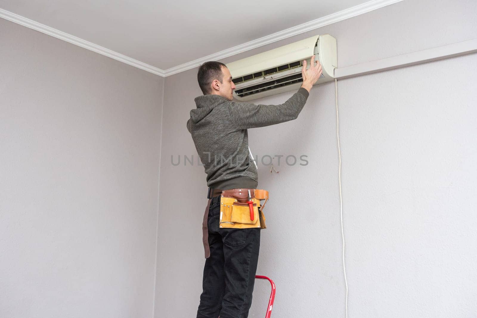 Male technician cleaning air conditioner indoors by Andelov13