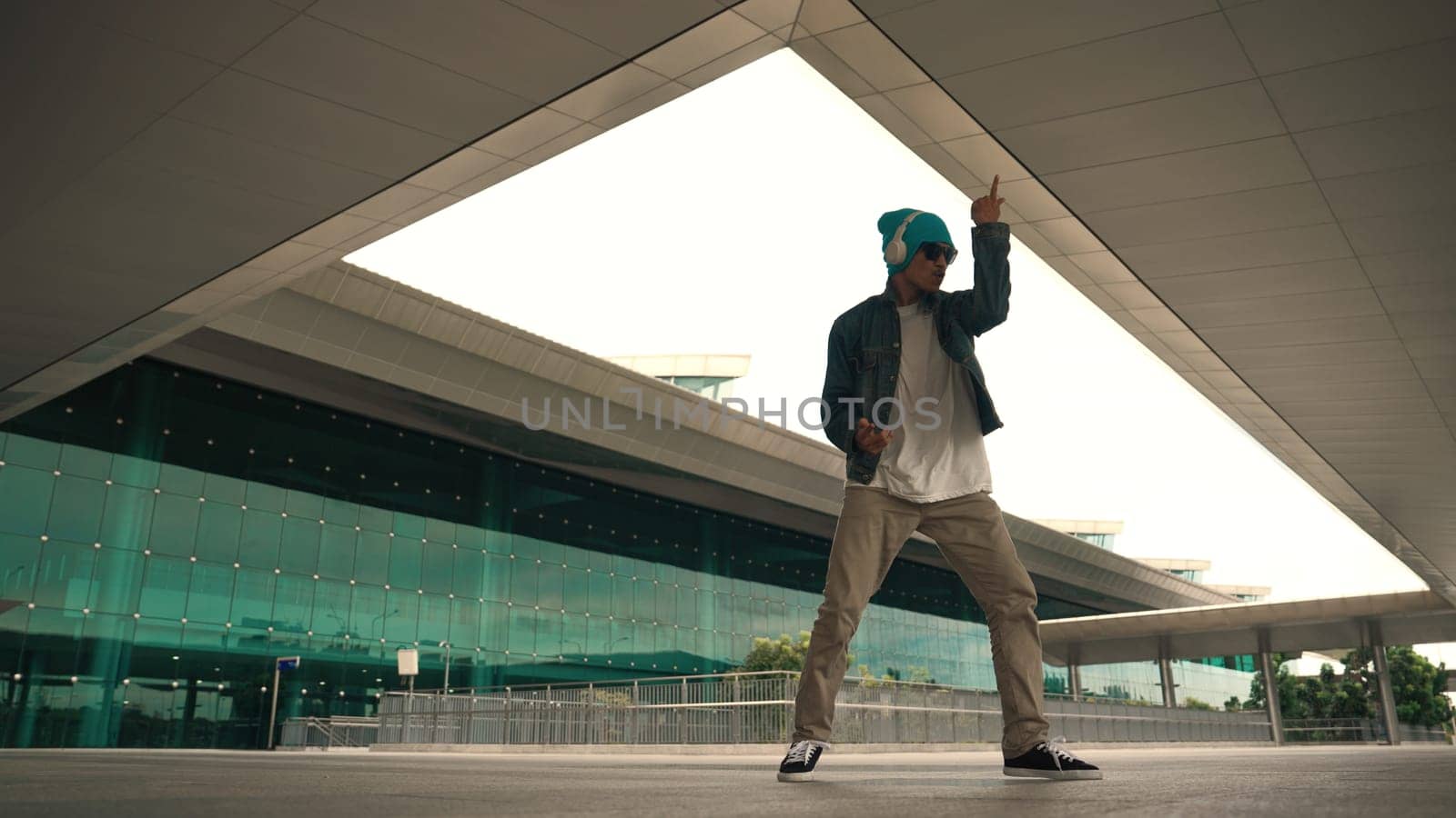Motion shot of happy hipster practice b boy dance with stylish cloth at building. Dancer enjoy show footstep performance. Modern lifestyle, break dancing. Slow motion. Outdoor sport 2024. Sprightly.
