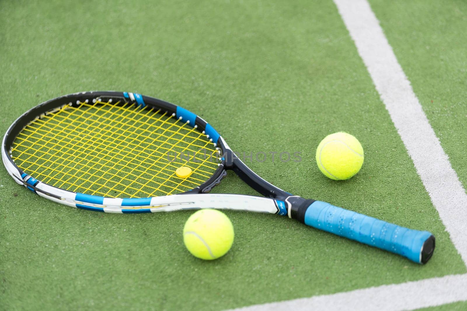 Tennis ball and racket on the ground of sunny outdoor grass tennis court. Summer, healthy lifestyle, sport and hobbies. High quality photo