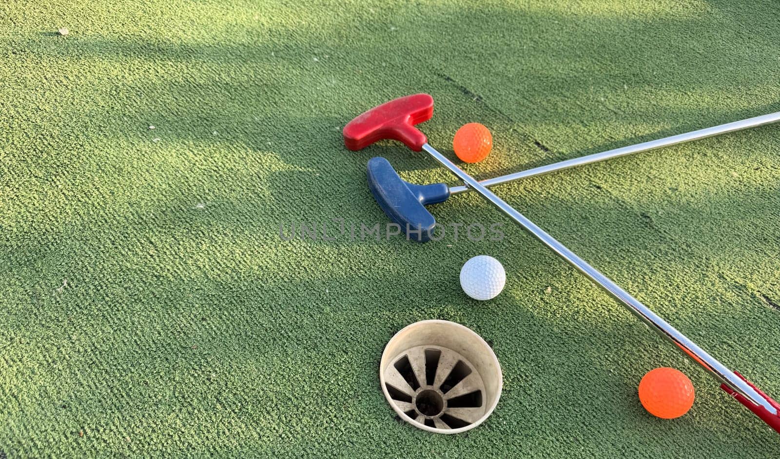Golf ball and golf club on green in the evening golf course with sunshine by Andelov13