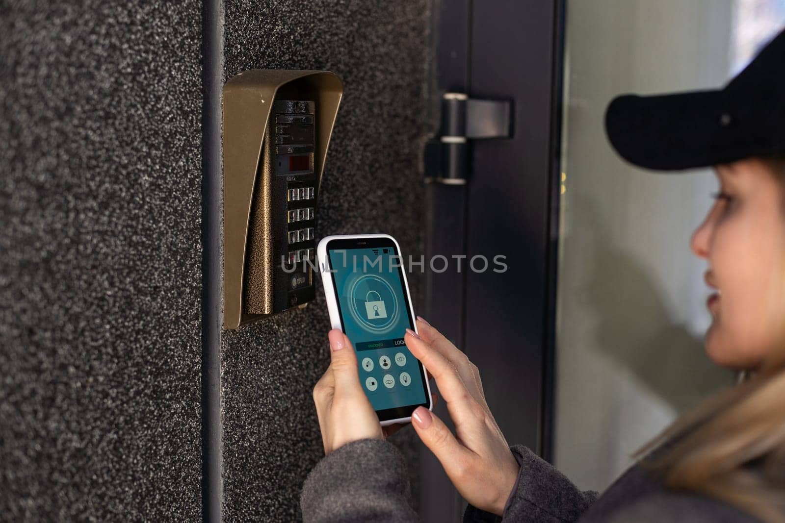 woman uses smartphone to open the door of his house. High quality photo
