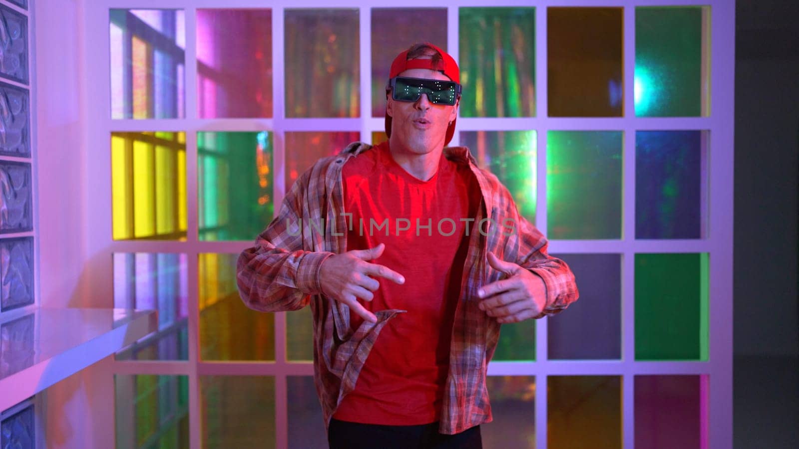 Funny break dancer moving freestyle step to hiphop while looking at camera. Crazy happy hipster dancing and performing street dancing while wear casual outfit and sunglasses in Led light. Regalement.