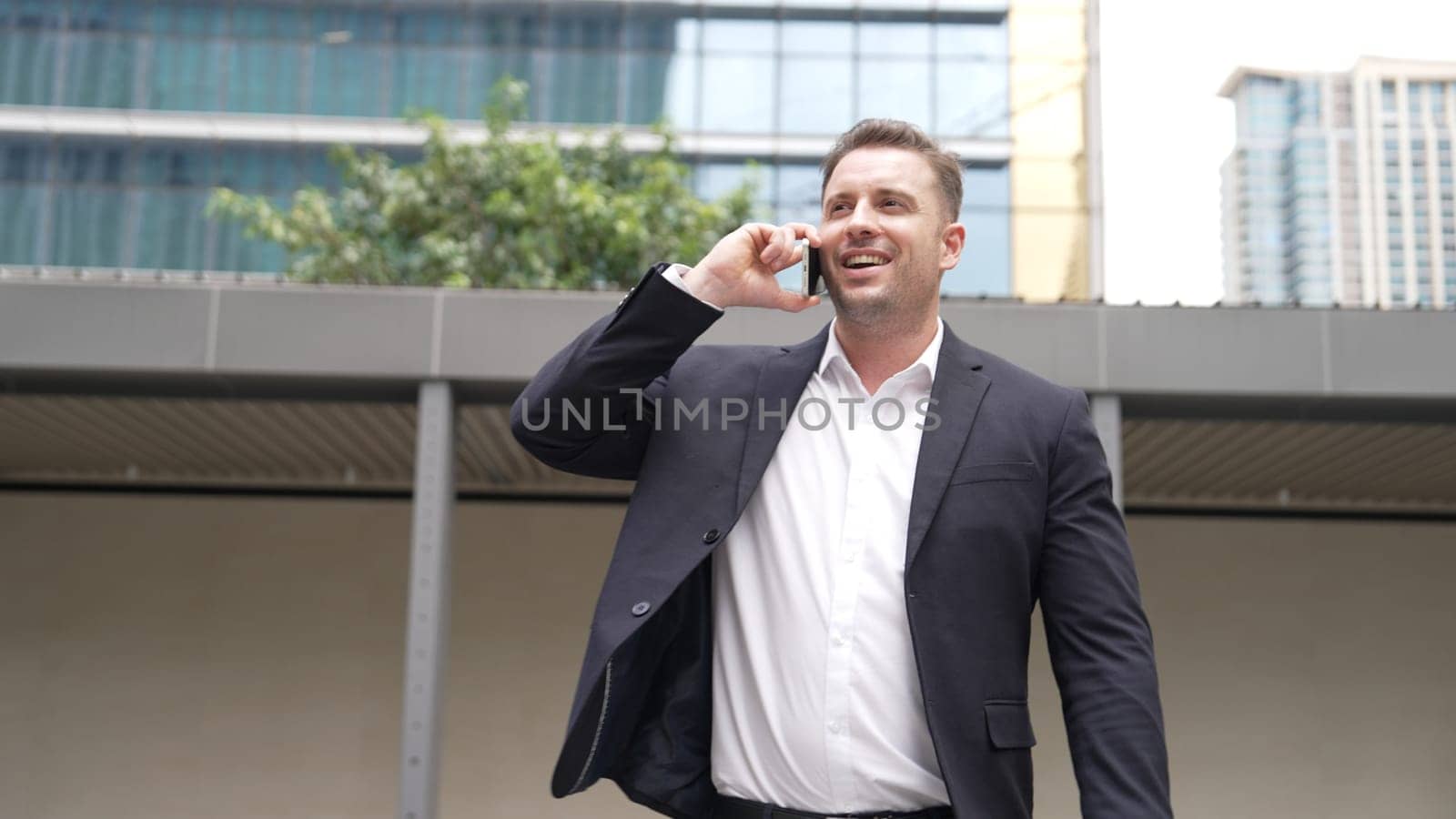 Skilled businessman calling his colleague to plan financial strategy while walking to workplace. Project manager using mobile phone to communicate with team while talking to phone. Lifestyle. Urbane.