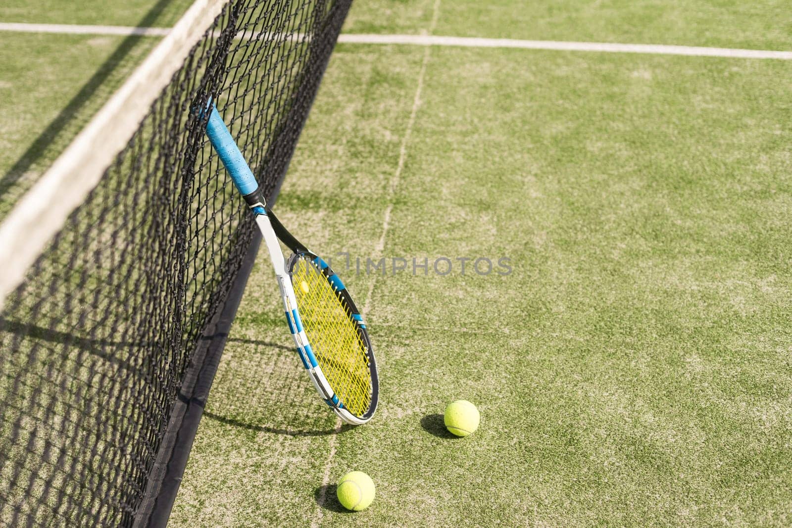 Tennis racquet and tennis balls at the net on the lines on a tennis court. . High quality photo