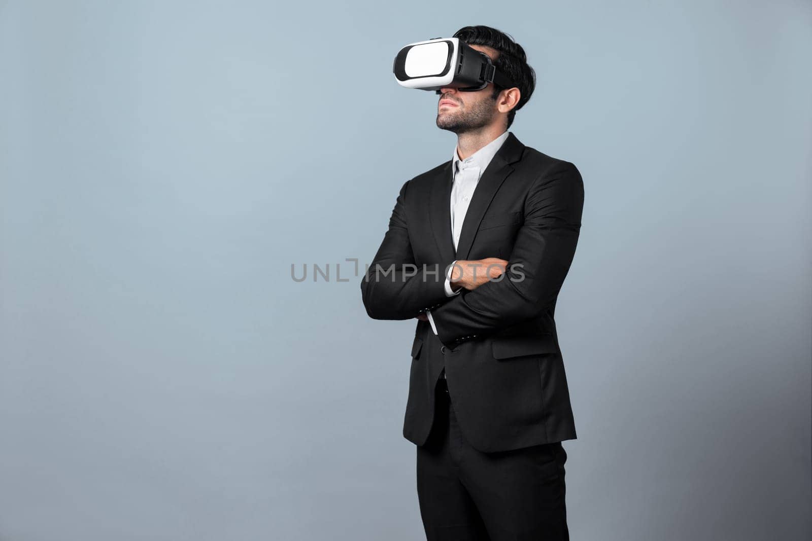 Smart business man crossing arms and standing with folded arm at white background. Professional manager looking at financial graph by using technology innovation to visit enter metaverse. Deviation.