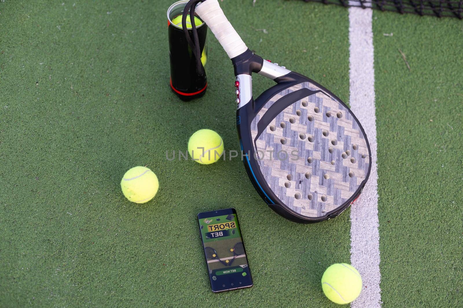 High angle view of mobile phone with tennis equipment on court background. High quality photo