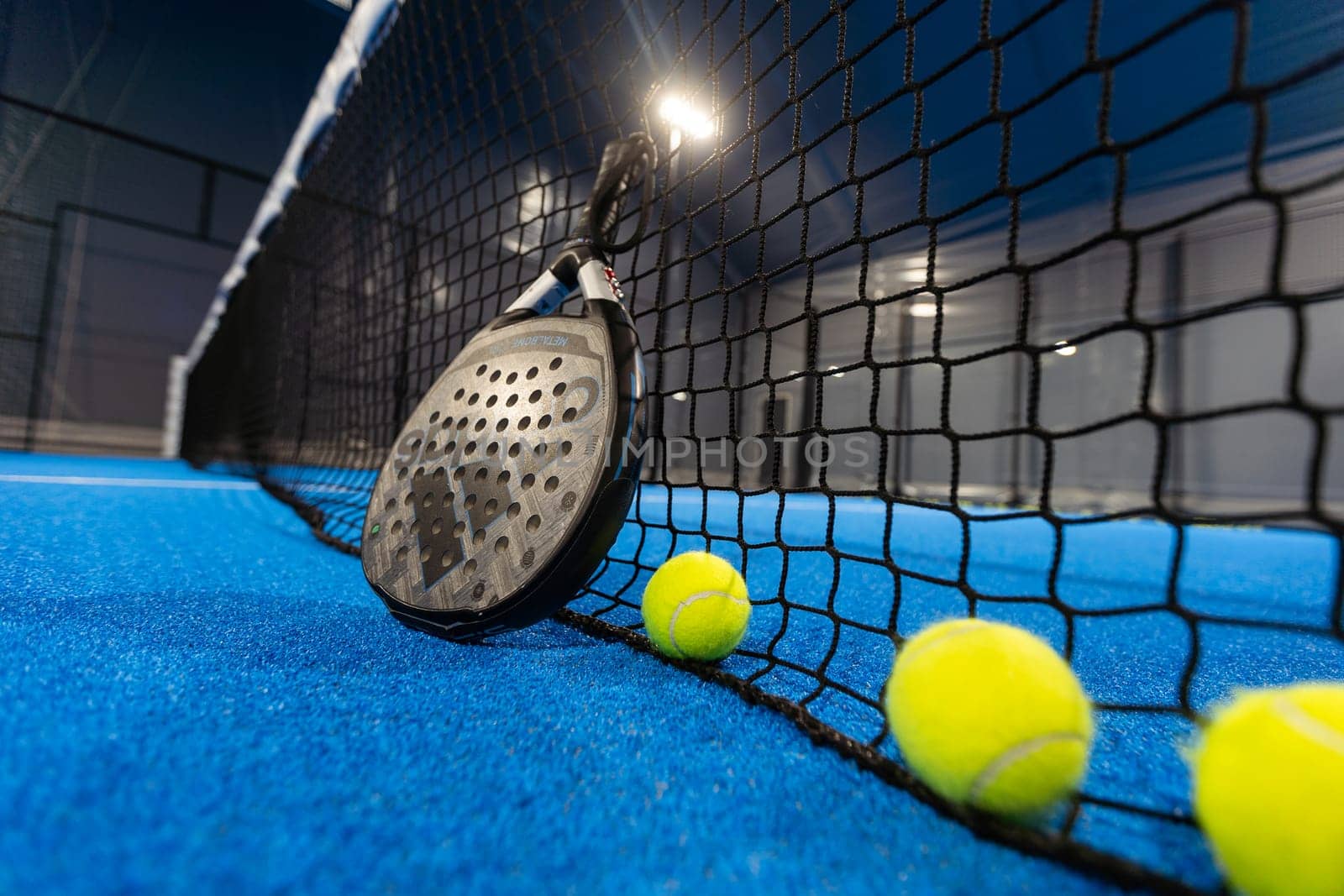 Kyiv, Ukraine, April 18, 2024. Black professional paddle tennis racket and ball with natural lighting on blue background. Horizontal sport theme poster, greeting cards, headers, website and app by Andelov13