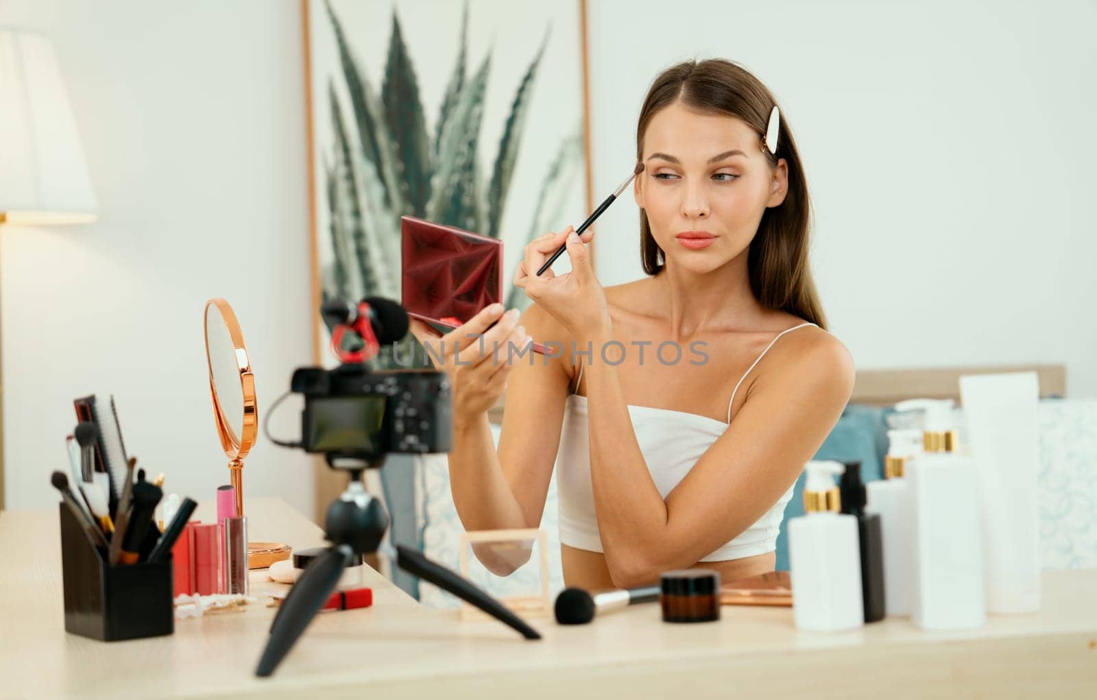 Young woman making beauty and cosmetic tutorial video content for social media. Beauty blogger smiles to camera while showing how to beauty care to audience or followers. Unveiling