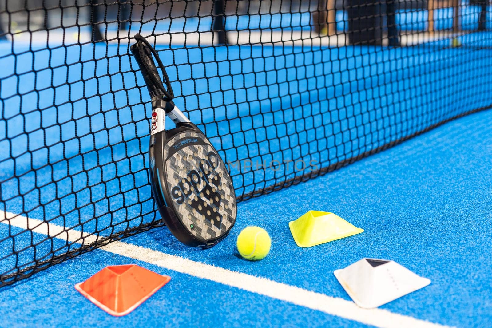 Kyiv, Ukraine, April 18, 2024. Black professional paddle tennis racket and ball with natural lighting on blue background. Horizontal sport theme poster, greeting cards, headers, website and app. High quality photo