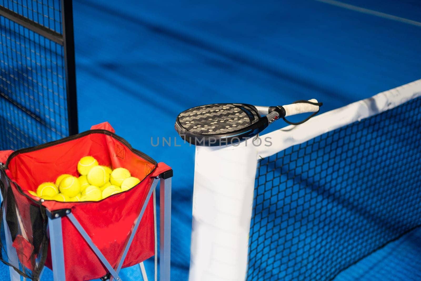 Black professional paddle tennis racket and ball with natural lighting on blue background. Horizontal sport theme poster, greeting cards, headers, website and app. High quality photo