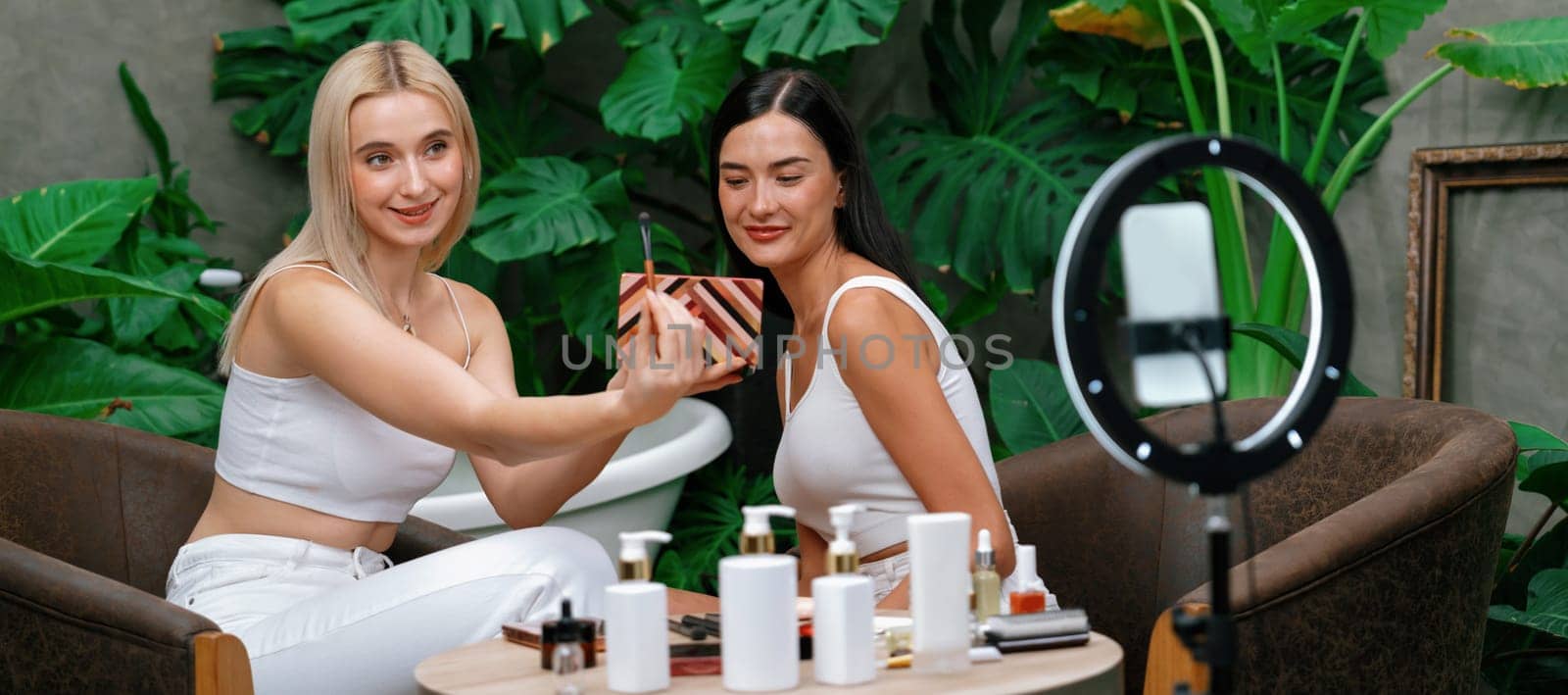 Two beautiful content creator making natural beauty and cosmetic tutorial on green garden. Beauty blogger show how to beauty care video to social medial audience using selfie stick.Panorama Blithe