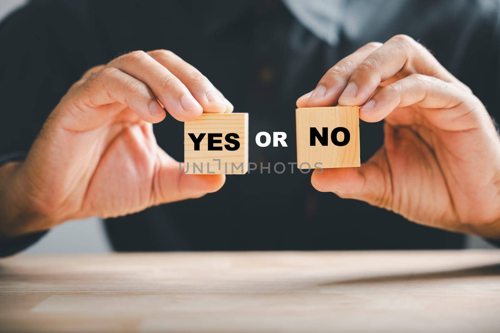 Hand holds Yes and No text on two wooden cubes, symbolizing Yes or No choice. True and false symbols for evaluation.